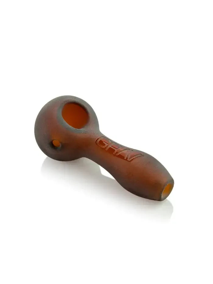 Eine matte, sandgestrahlte Glaspfeife in Löffelform in einem dunklen Bernsteinton mit tiefem Kopf und dezentem „GRAV“-Logo auf dem Griff.