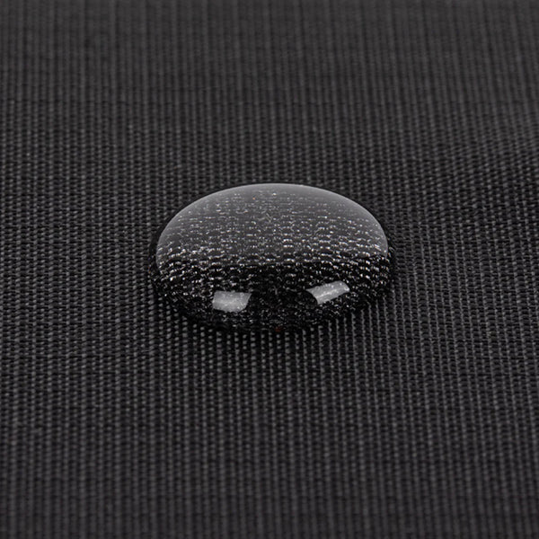 Nahaufnahme eines Wassertropfens auf dem schwarzen, strukturierten Stoff der PAX-Tasche, um das wasserabweisende Material zu demonstrieren.