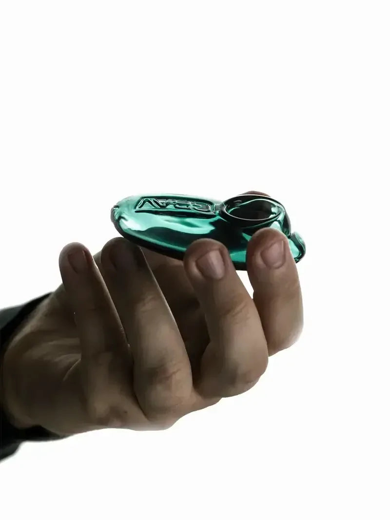 Eine Person hält eine kompakte, smaragdgrüne Pebble-Pfeife aus Glas, die ihr handliches, ergonomisches Design und das geprägte Logo zeigt.