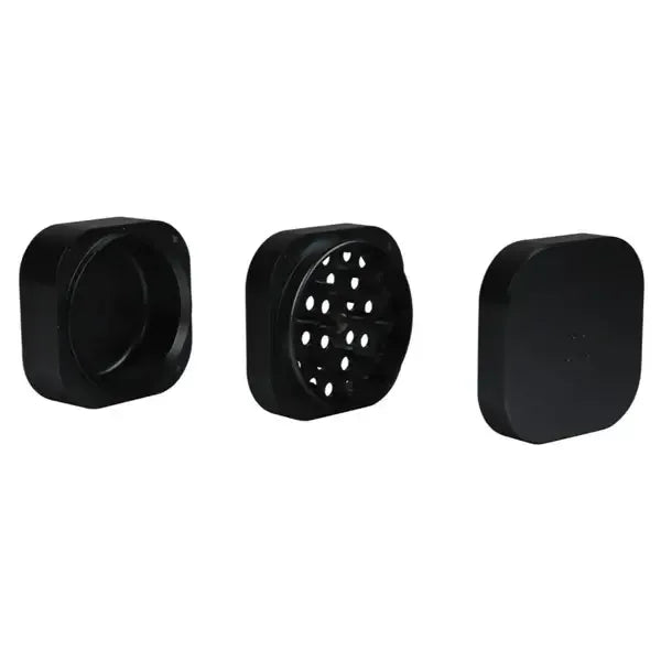 Die drei Einzelteile eines mattschwarzen, quadratischen Grinders: das Bodenfach, die mittlere Mahlkammer und der Deckel.