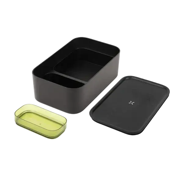 Eine geöffnete große, mattschwarze PAX-Aufbewahrungsdose mit danebenliegendem Deckel und einer transparenten grünen Innenschale, die die leeren unterteilten Fächer zeigt.