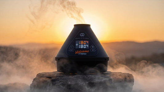 Volcano von Storz & Bickel steht auf einem Stein. Im Hintergrund ein Sonnenuntergang und Rauch..n