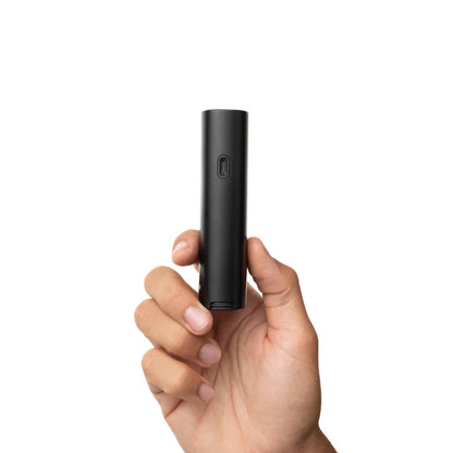 Eine Hand hält den kompakten, schwarzen PAX Vaporizer aufrecht vor einem weißen Hintergrund, um seine geringe Größe zu verdeutlichen.