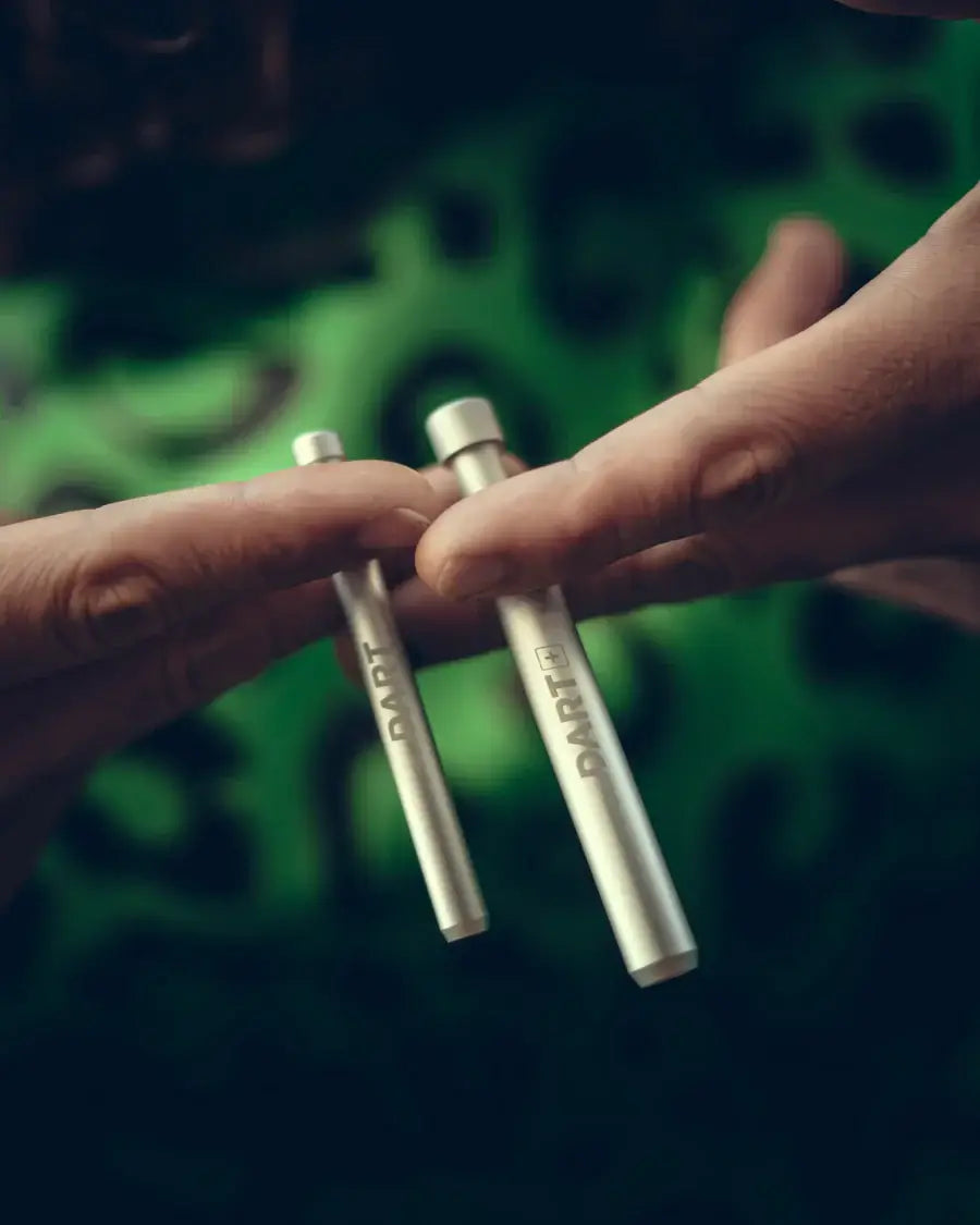 Hands holding two sizes of THE DART pipes, showcasing their compact design for easy use and portability.